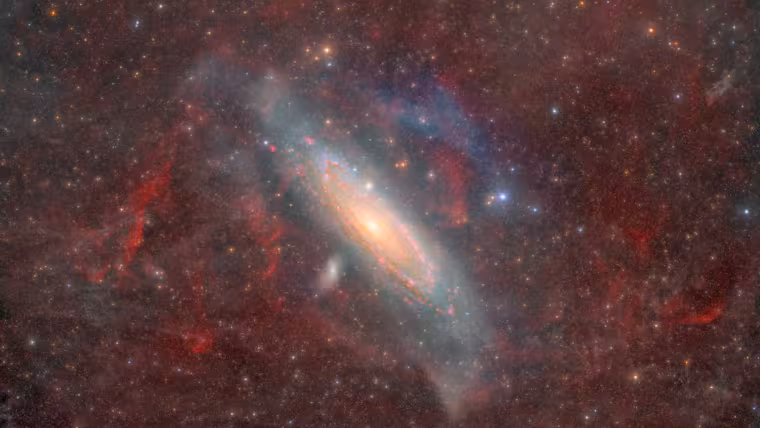 Galaxie v Andromedě prosvítá plynem a prachem Mléčné dráhy